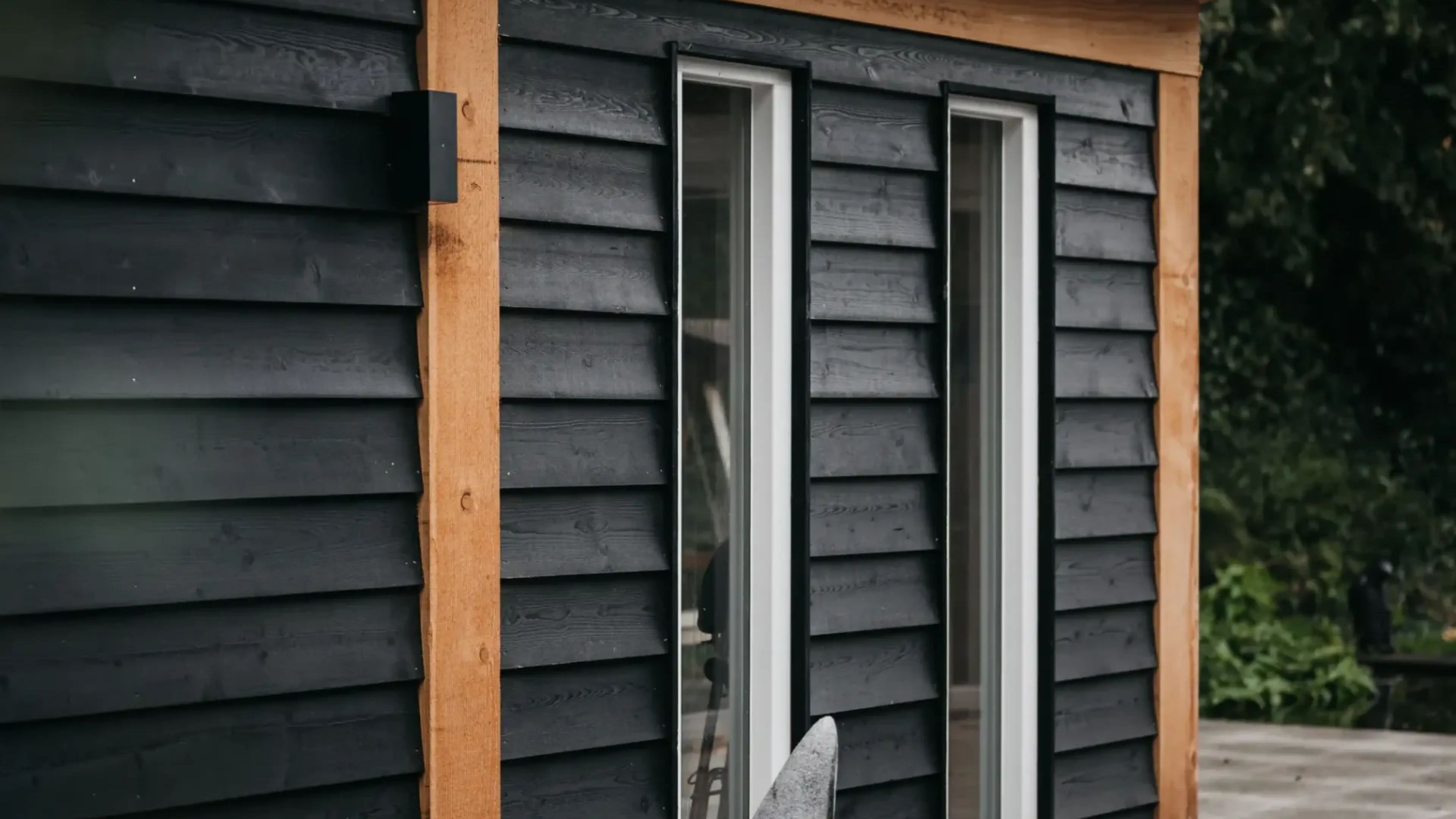 Zwart houten tuinhuis met lariks kozijnen