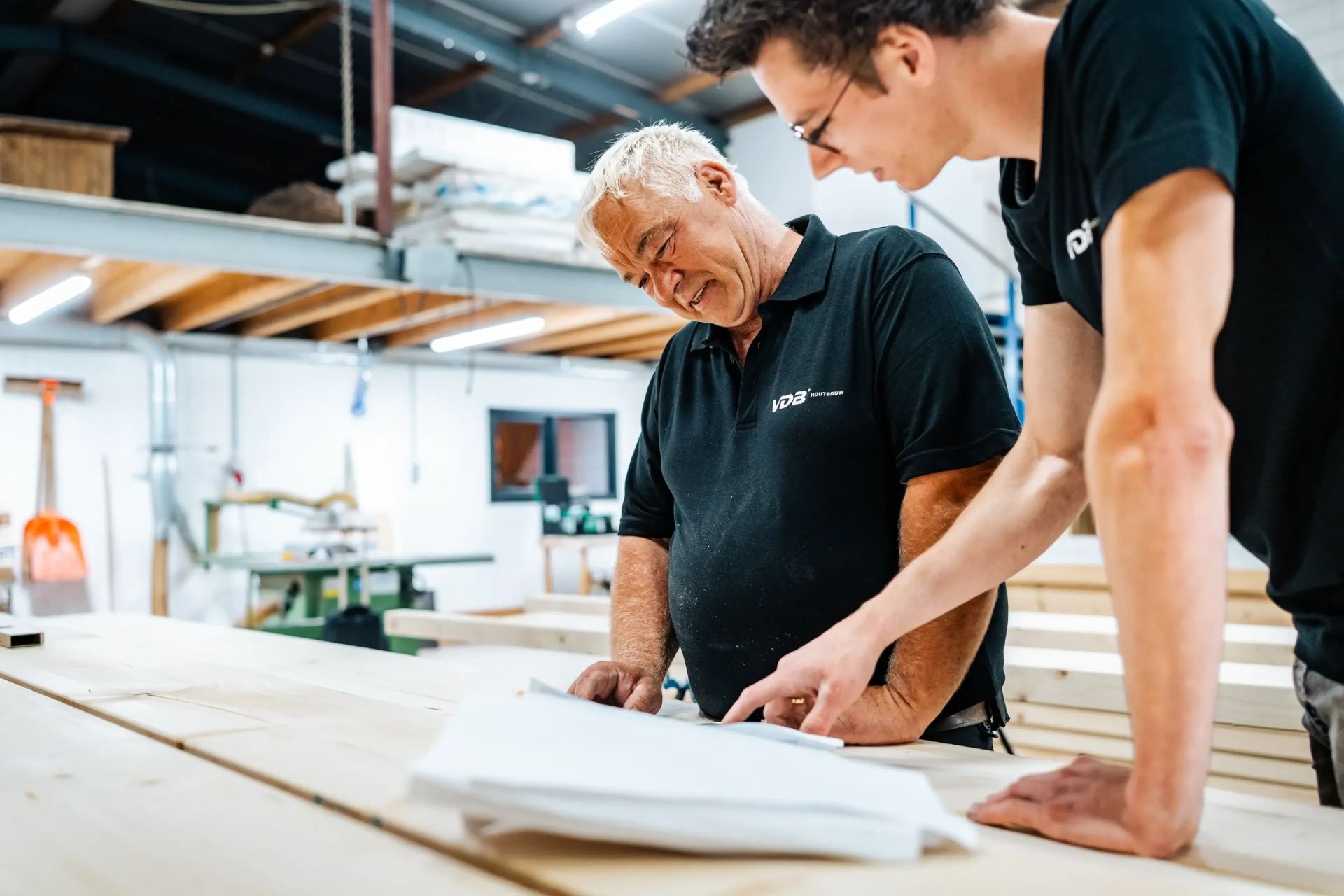 Twee vakmensen bekijken een bouwtekening in de werkplaats